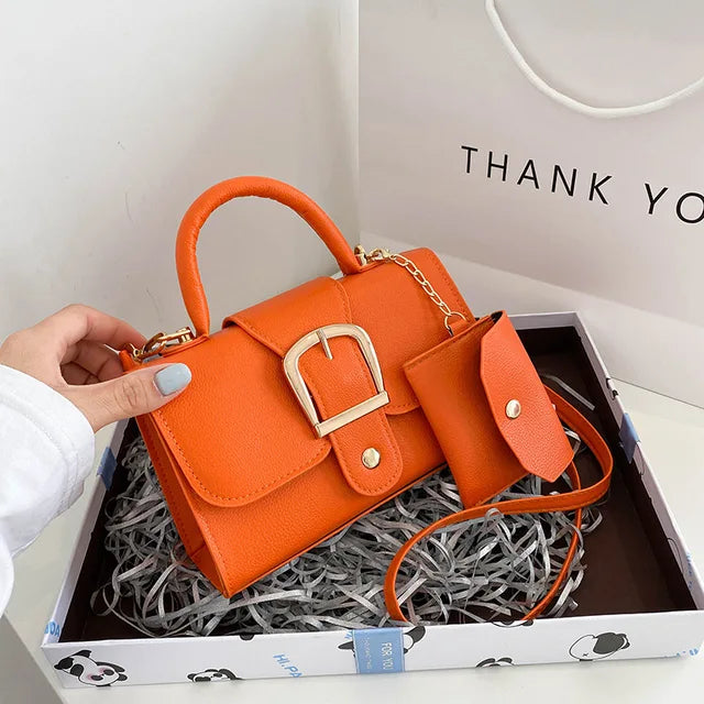 Orangefarbene Handtasche aus Leder mit Schnalle und passendem Etui in Geschenkbox.
