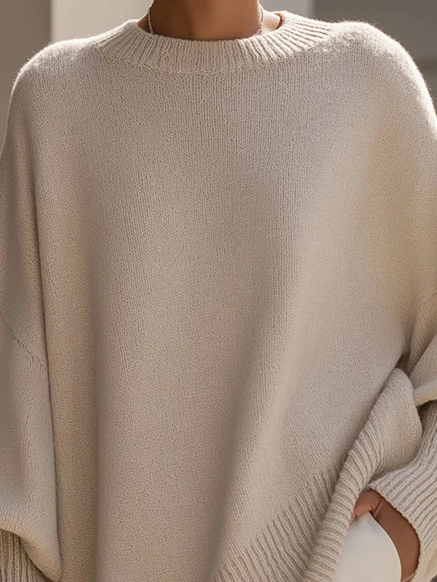 Nahaufnahme des beigen Pullovers im Brustbereich mit gerippter Halsblende und grober Strickstruktur, Hand in der Hosentasche. 2