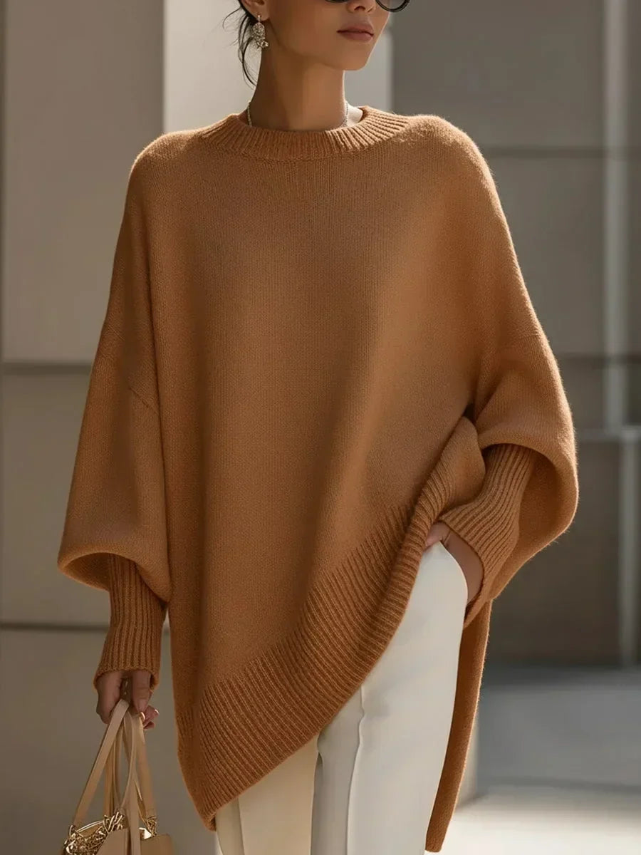Karamellbrauner Pullover mit Fledermausärmeln und gerippter Saumkante, getragen mit weißer Hose und heller Handtasche. 12