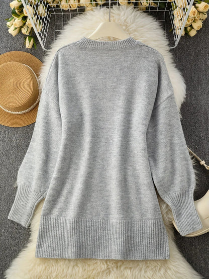 Hellgrauer Pullover von hinten auf einem weißen Fellteppich liegend, daneben ein Strohhut und Rosen, mit Rippsaum und Rippbündchen. 10