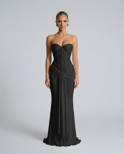 Schwarzes trägerloses Maxikleid mit perlenbesetztem Korsagenoberteil und drapiertem Tuch, frontal von einem Model getragen 1