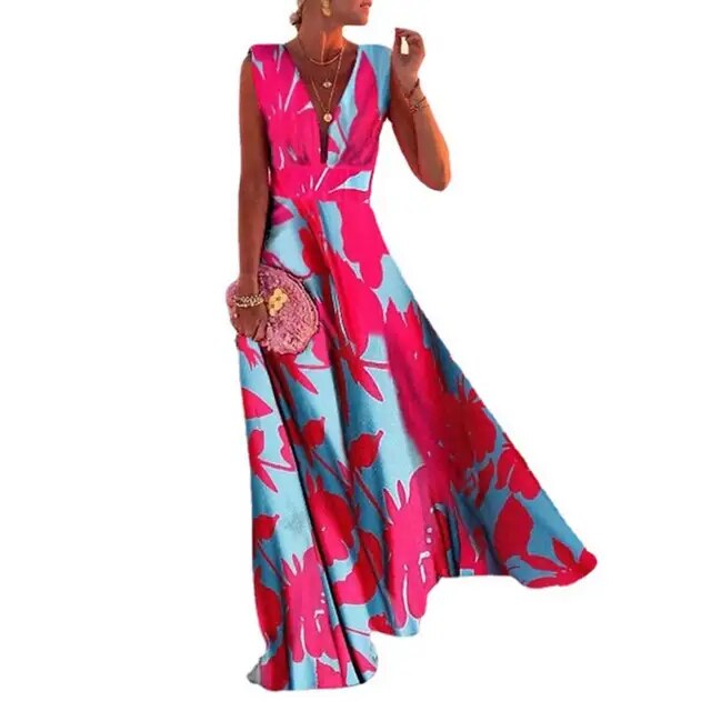 Frau in langem, ärmellosem Kleid mit pink-blauem Blumenmuster, hält rosa Tasche.