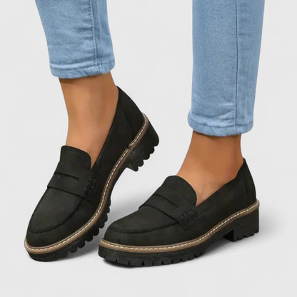 Schwarze Loafer mit grober Profilsohle, getragen zu hellblauen Jeans, Ansicht von vorne seitlich 1