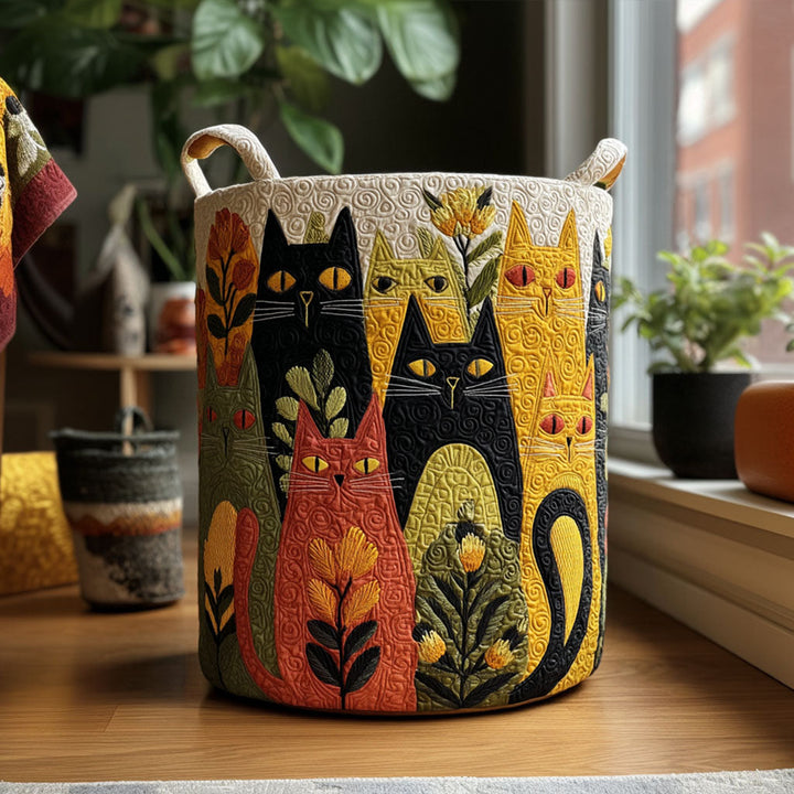 Gesteppter Korb mit buntem Katzenmotiv in Schwarz, Gelb, Rot und Grün steht auf einem Holzboden vor einem Fenster mit Zimmerpflanzen. 1