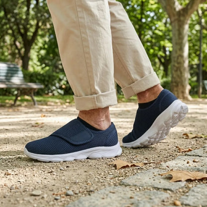 Person in beigen Hosen geht im Park und trägt die marineblauen Klettschuhe mit weißer Sohle auf Kiesweg. 2