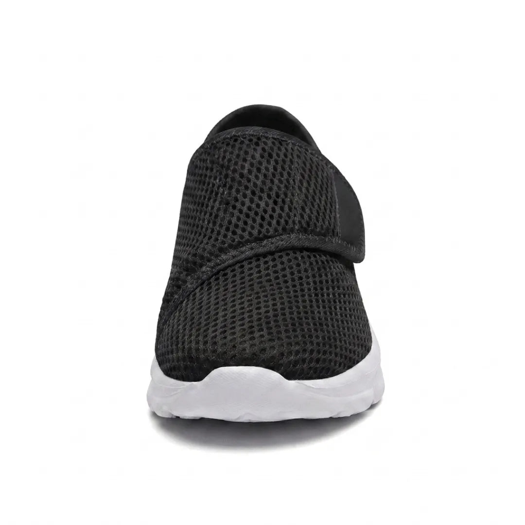 Frontansicht eines schwarzen Netzschuhs mit Klettband über dem Rist und weißer Sohle, die die breite Form der Schuhspitze zeigt. 26