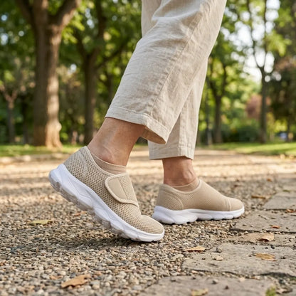 Person in hellen Leinenhosen geht auf einem Parkweg mit Kies in beigen Netzschuhen mit Klettverschluss und weißer Sohle. 29