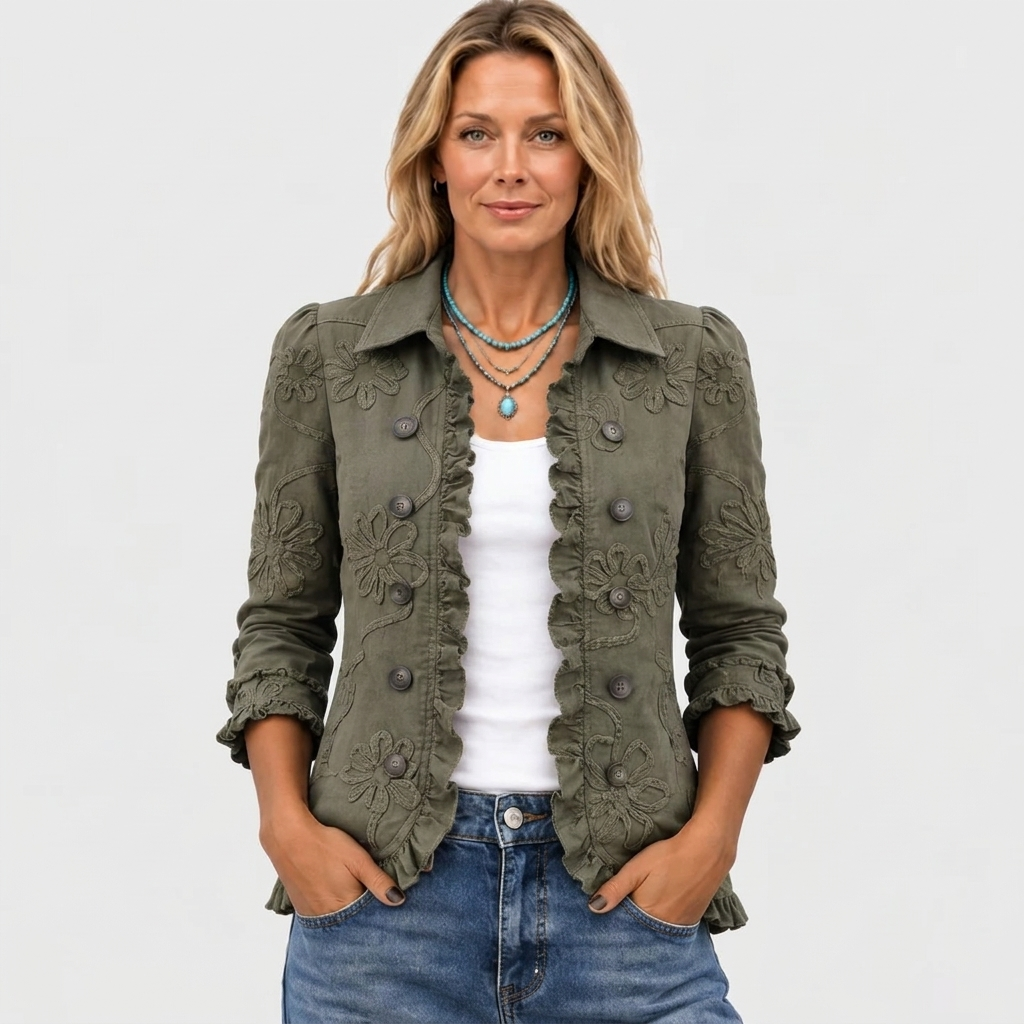 Frontansicht am Model: olivgrüne, offen getragene Jacke mit Rüschen und Blumenstickerei, dazu weißes Top, Jeans und türkisfarbene Halskette. 2