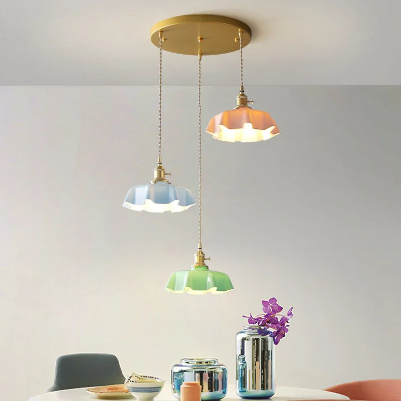 Dreifache Retro-Hängelampe aus Messing und Glas in Pastellfarben über Esstisch.