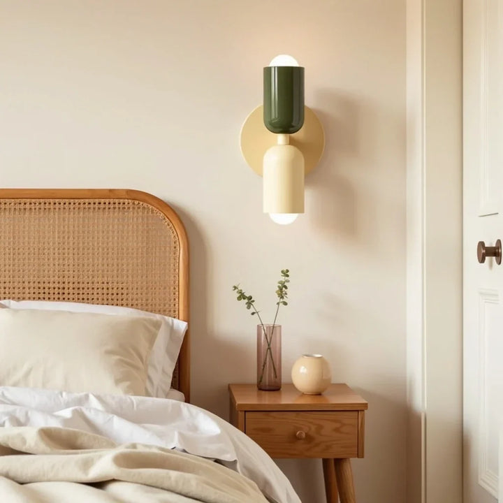 Wandleuchte mit dunkelgrünem oberem und cremefarbenem unterem Schirm neben einem Bett mit Rattan-Kopfteil über einem Holz-Nachttisch. 13