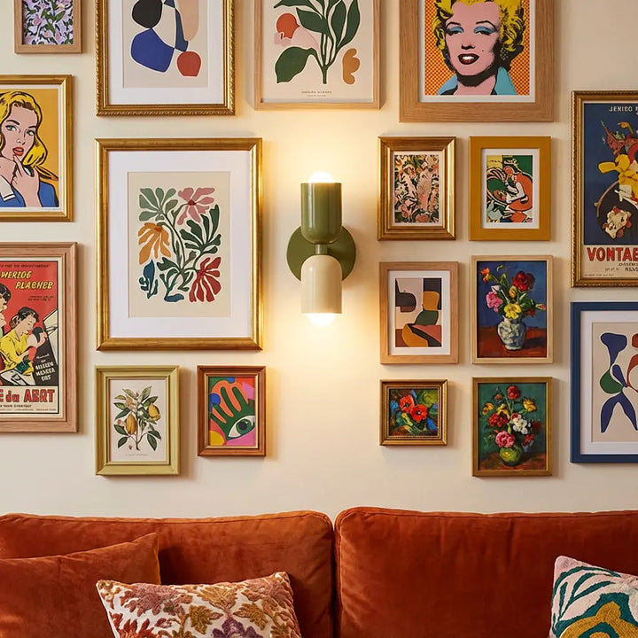 Grün-cremefarbene Wandleuchte leuchtet mitten in einer Bildergalerie mit vielen gerahmten Kunstdrucken über einem orangefarbenen Samtsofa. 6