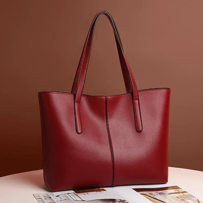 Rote Tote-Tasche schräg von vorn auf einem Tisch vor brauner Wand, mit Zeitschrift im Vordergrund 3