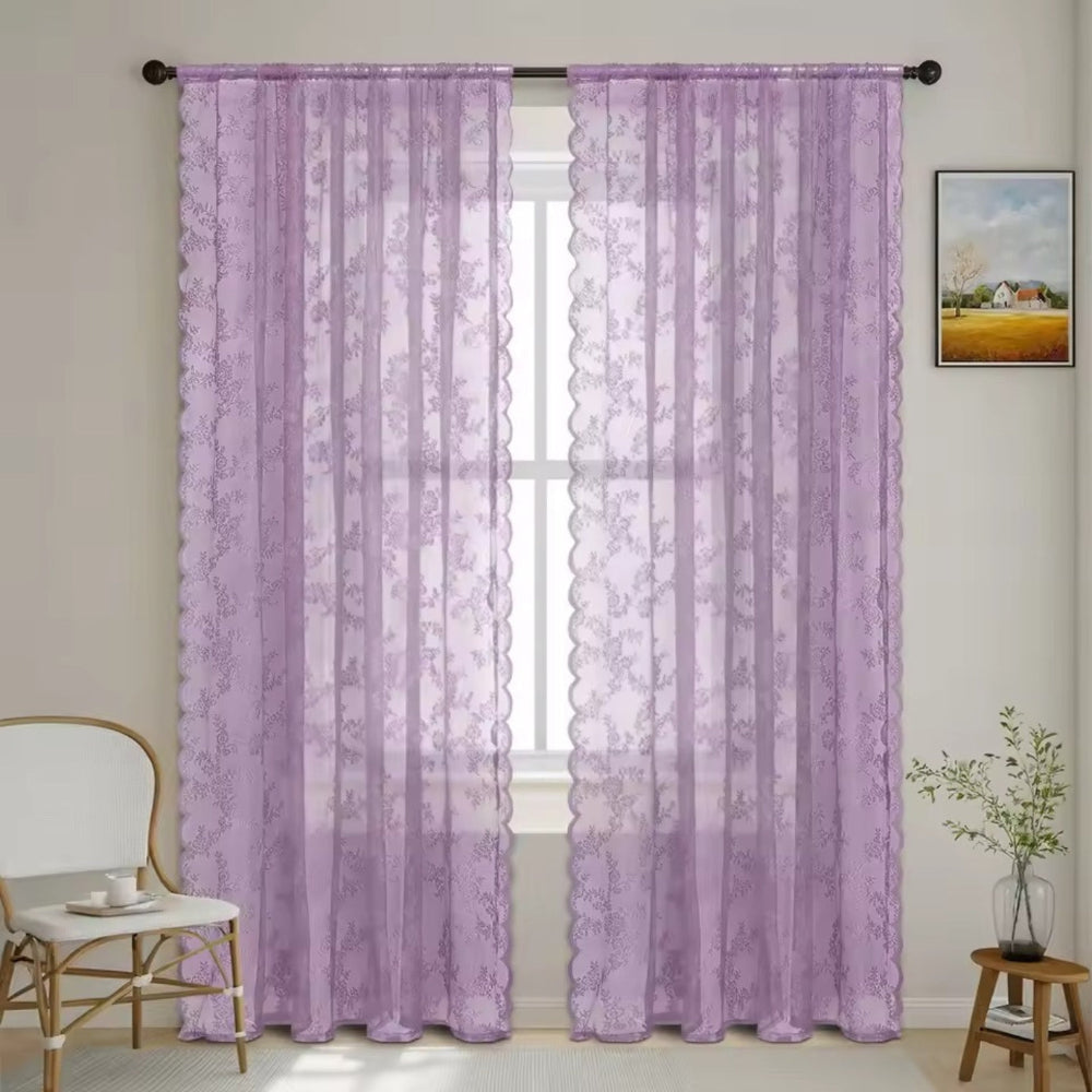 Zwei fliederfarbene Schals mit Blumenmuster und gewellter Kante an dunkler Stange vor einem hellen Fenster in einem Wohnraum. 10