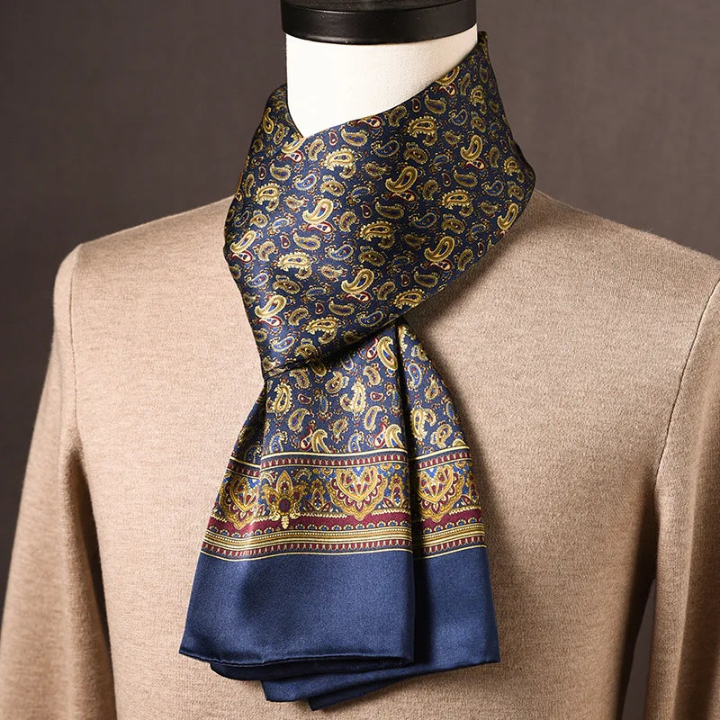 Marineblauer Seidenschal mit goldenem Paisleymuster und weinroter Zierbordüre, auf einer Büste mit beigem Pullover drapiert. 12