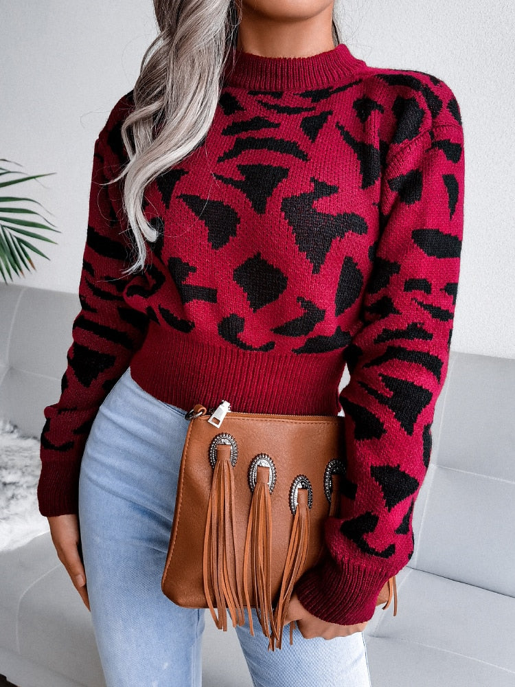 Frau in rotem Leopardenpullover, blaue Jeans, braune Fransenhandtasche, modisch, stilvoll.