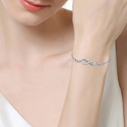 Silbernes Unendlichkeitsarmband am Handgelenk einer Frau, eleganter Schmuck, modisches Accessoire.