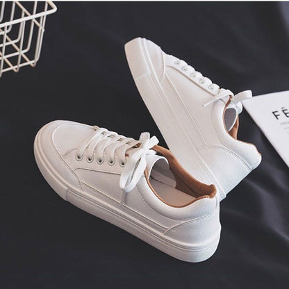 Weiße Damen-Sneaker aus Leder, modisch, bequem, mit Schnürsenkeln, auf schwarzem Hintergrund.