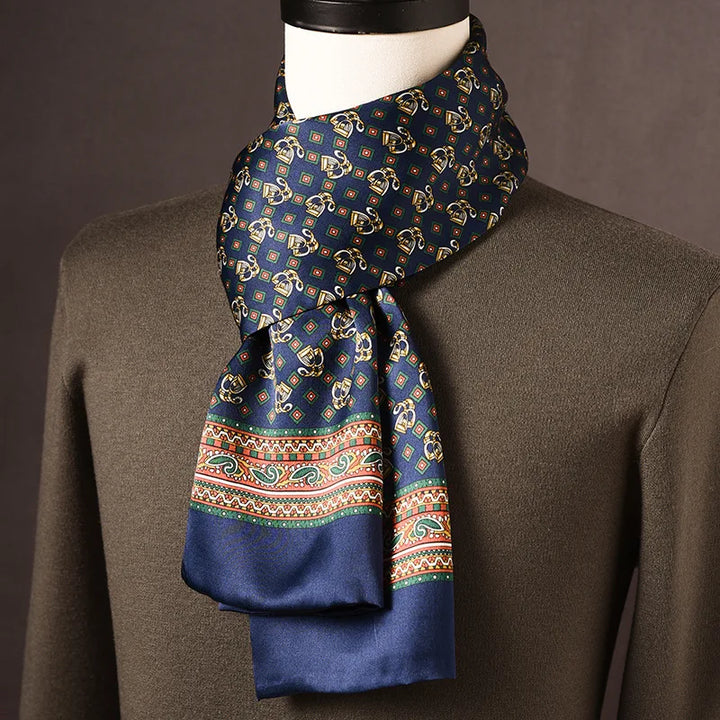 Marineblauer Seidenschal mit goldenen Motiven, bunter Paisley-Bordüre und blauer Kante, um eine Büste mit grünem Pullover. 20