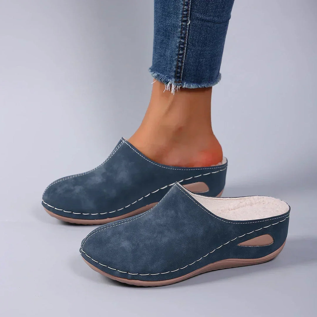 Blaue Pantoffeln mit Ziernähten und weichem Fleecefutter, getragen zu Jeans, Blick von der Seite auf die Aussparung. 4