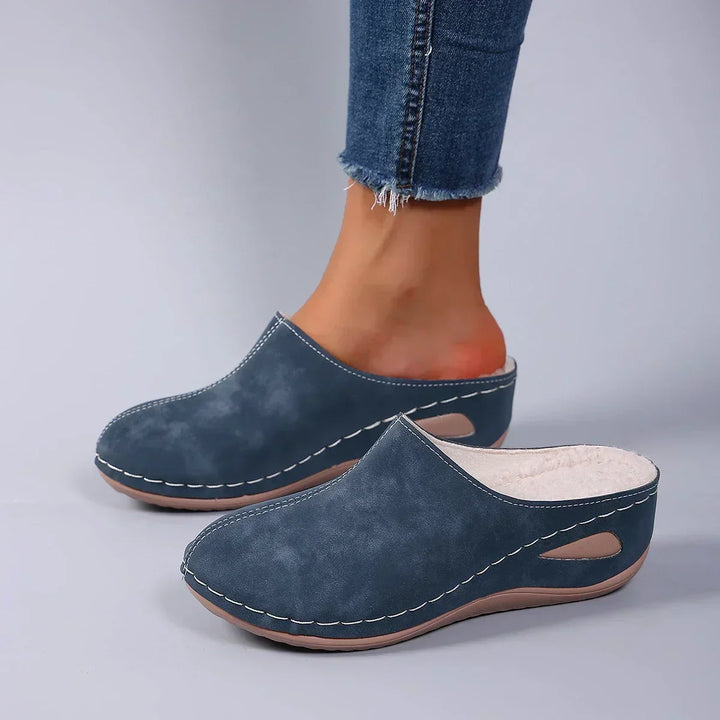 Blaue Pantoffeln mit Ziernähten und weichem Fleecefutter, getragen zu Jeans, Blick von der Seite auf die Aussparung. 4