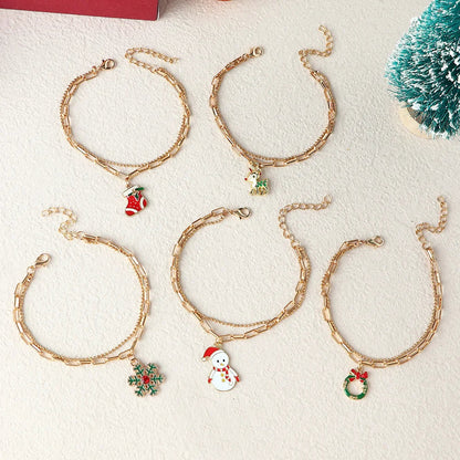 Fünf goldene Weihnachtsarmbänder mit Anhängern: Schneemann, Kranz, Schneeflocke, Stiefel, Baum.