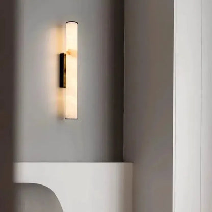 Leuchtende Wandlampe mit dunklen Kappen an grauer Wand über einer weißen geschwungenen Ablage, daneben eine weiße Wandkante. 20