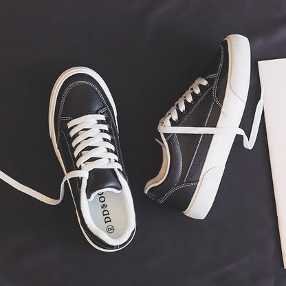 Schwarze Leder-Sneaker mit weißen Schnürsenkeln auf dunklem Hintergrund, modisch und bequem.