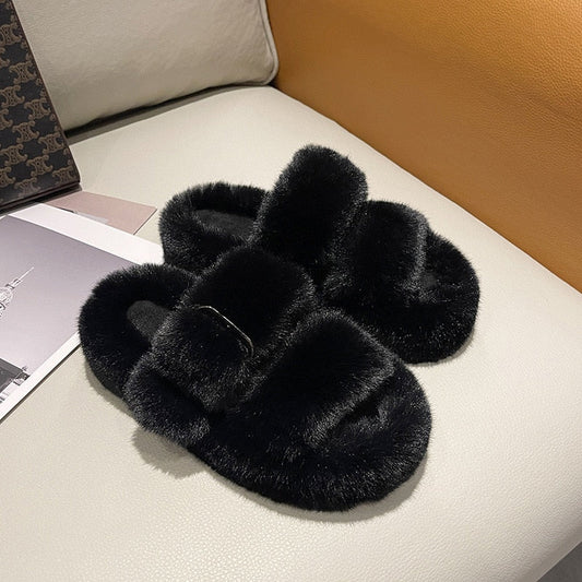 Schwarze flauschige Hausschuhe aus Kunstfell auf beigem Sofa, gemütliche Damenmode.