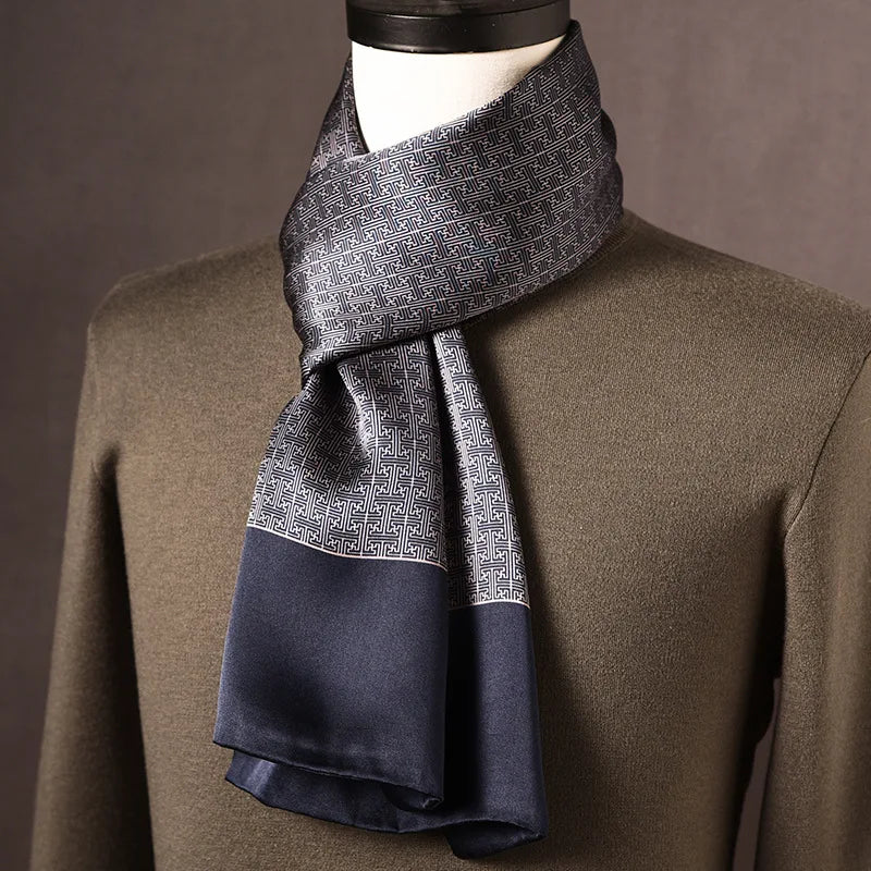 Grau-blauer Seidenschal mit geometrischem Mäandermuster und dunkelblauer Kante, an einer Büste mit olivgrünem Pullover. 10