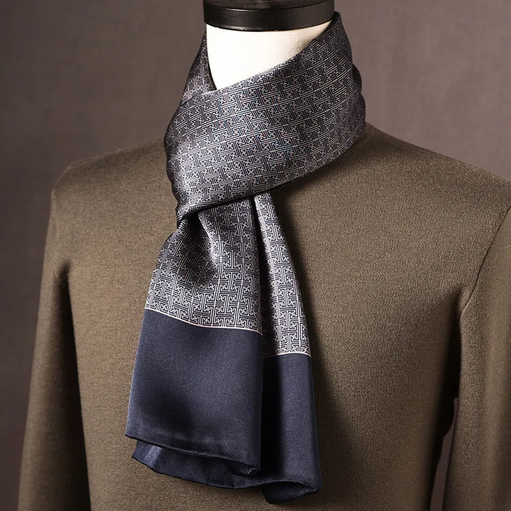 Grau-blauer Seidenschal mit geometrischem Mäandermuster und dunkelblauer Kante, an einer Büste mit olivgrünem Pullover. 10
