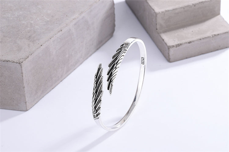 Silberarmreif mit Federdesign, eleganter Schmuck, Damenarmband, modisches Accessoire.
