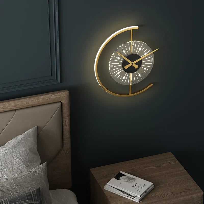 Moderne Wanduhr aus Metall in Gold, rund, mit LED-Beleuchtung, über Nachttisch im Schlafzimmer.