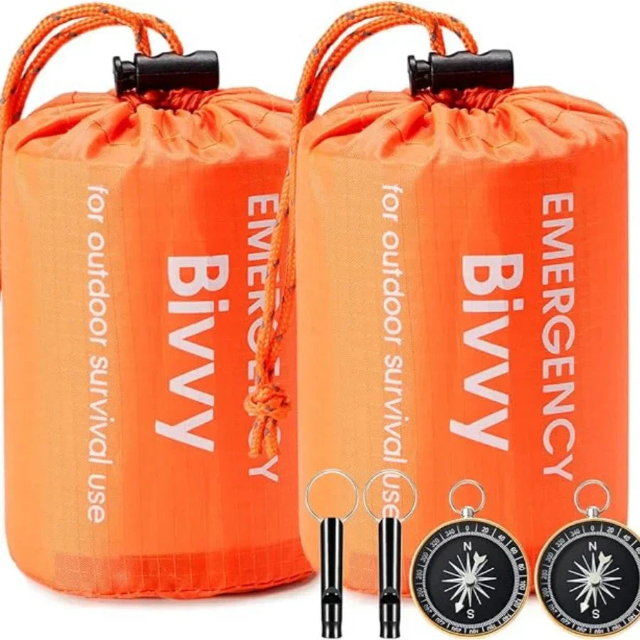 Zwei orange Notfall-Biwaksäcke mit Kompass und Pfeife für Outdoor-Überleben.