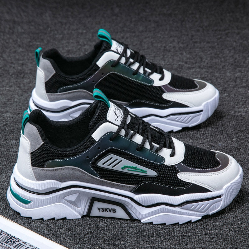 Schwarze und weiße Sportschuhe, atmungsaktiv, mit grünen Akzenten, auf grauem Hintergrund.