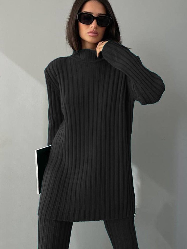 Frau in schwarzem, geripptem Strickpullover mit Rollkragen und Sonnenbrille.