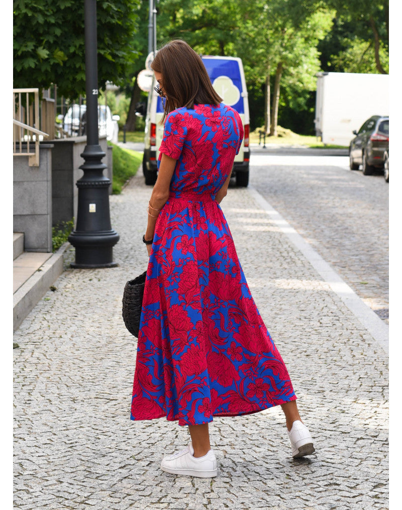 Frau in rotem, geblümtem Maxikleid auf gepflasterter Straße, Sommermode, Rückansicht.