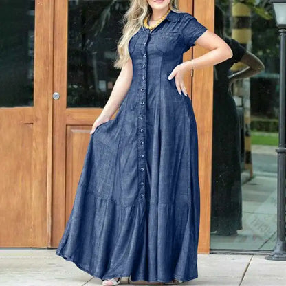 Frau in langem, blauem Jeanskleid mit Knopfleiste vor Holztür.