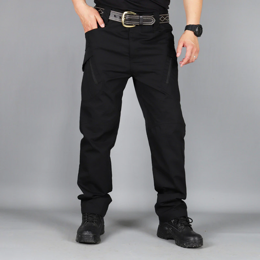 Mann in schwarzer taktischer Hose, schwarzem Gürtel und Stiefeln, ideal für Outdoor-Aktivitäten.