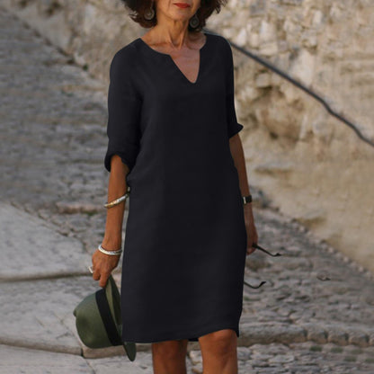 Frau in schwarzem Kleid mit Hut auf Kopfsteinpflasterweg, elegantes Outfit, Sommermode.