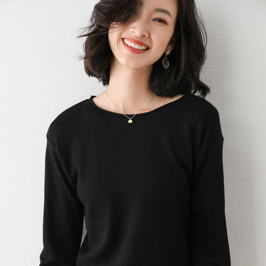 Frau in schwarzem Pullover, lächelnd, mit kurzen Haaren und goldener Halskette.