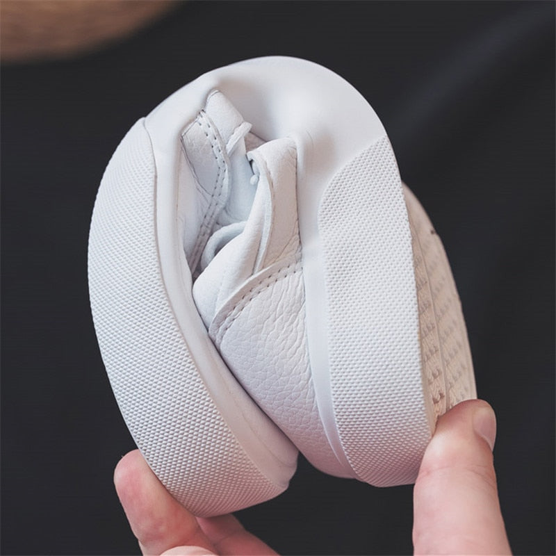 Weiße, flexible Babyschuhe aus Leder, rutschfeste Sohle, ideal für Kleinkinder.