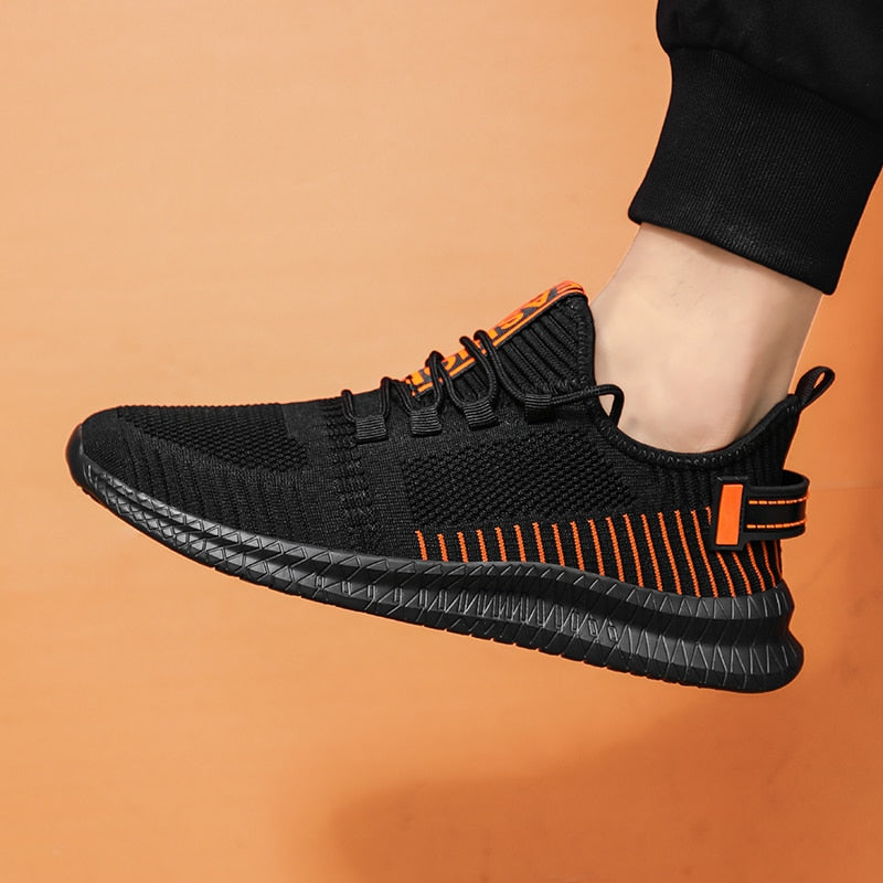 Schwarzer Sneaker mit orangefarbenen Akzenten, atmungsaktives Mesh, sportlich, Herrenmode.