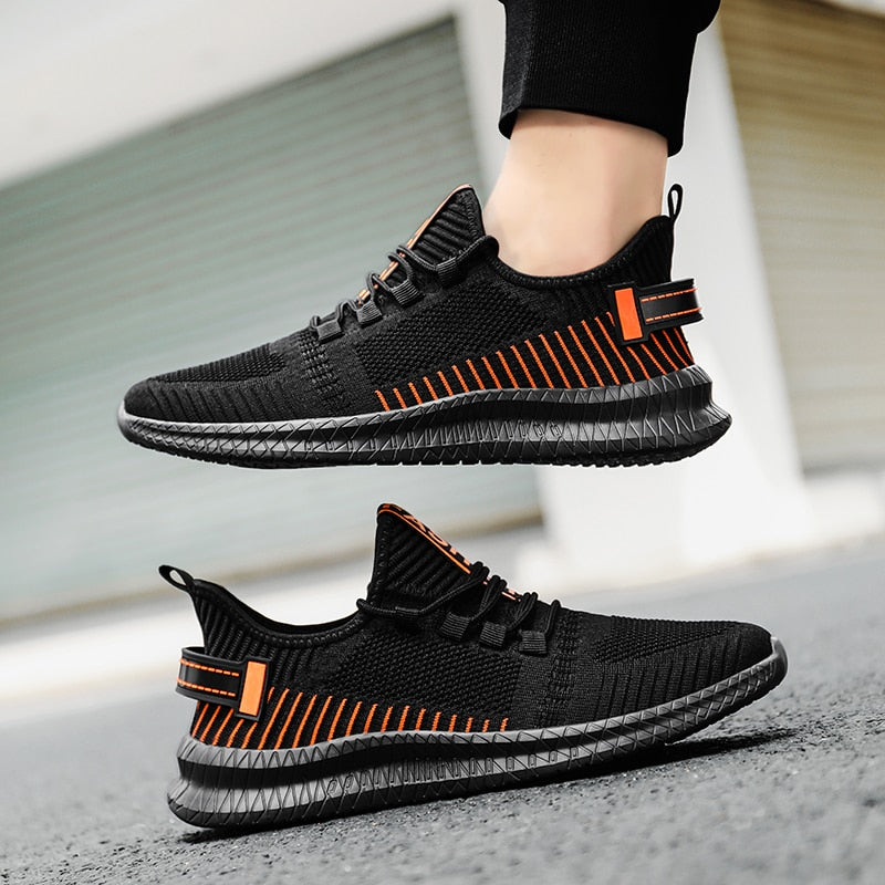 Schwarze Sportschuhe mit orangefarbenen Akzenten, atmungsaktives Mesh, rutschfeste Sohle.