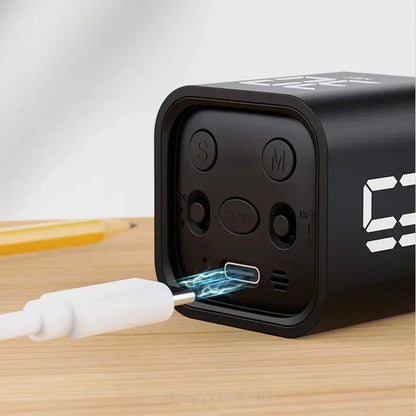 Schwarzer digitaler Wecker mit USB-Ladeanschluss auf Holztisch.