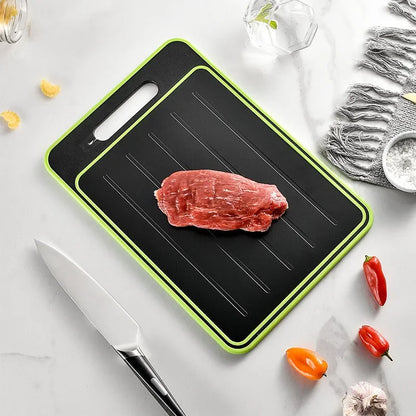 Schwarzes Schneidebrett mit grünem Rand, rohes Fleisch, Küchenmesser, Paprika, Marmorhintergrund.