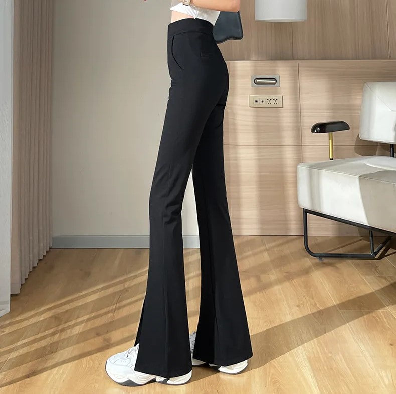 Frau trägt schwarze Schlaghose, weiße Sneaker, modernes Wohnzimmer, stilvolle Mode.