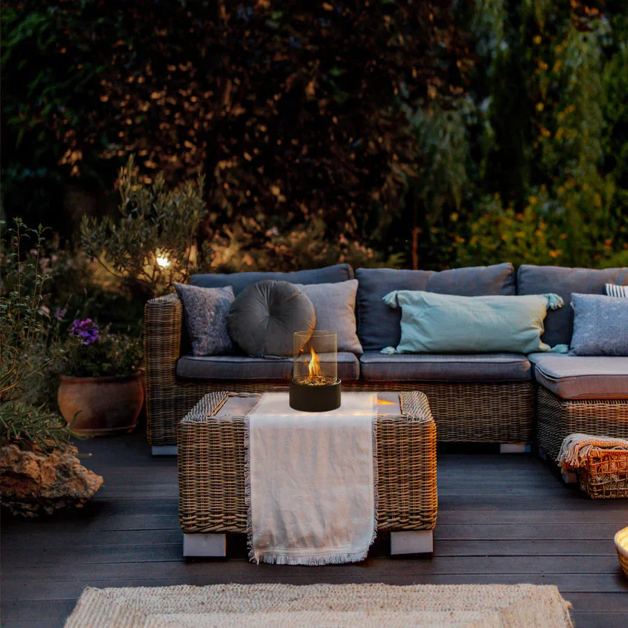 Rattan-Sofa-Set mit Kissen auf Holzterrasse, Garten, Abendbeleuchtung, gemütliche Atmosphäre.