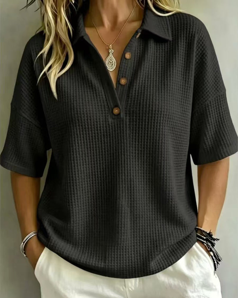 Frontansicht in Schwarz: Waffelstrick-Polo mit Knopfleiste, getragen mit heller Hose und Armschmuck 5