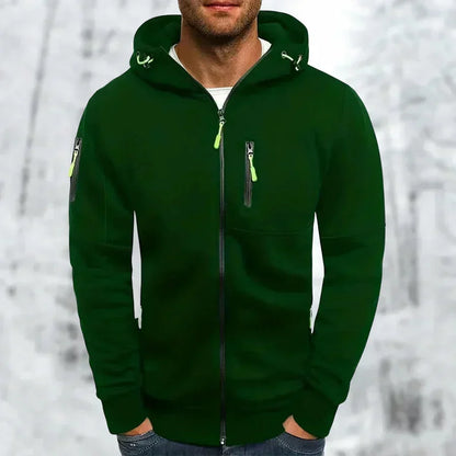 Mann im dunkelgrünen Kapuzenpullover mit neongrünen Reißverschlusszügen und Kordelzug an der Kapuze vor verschneitem Hintergrund. 6
