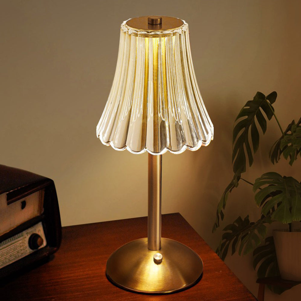 Goldene Tischlampe mit geriffeltem Glasschirm auf Holztisch, Vintage-Stil, Wohnzimmerbeleuchtung.
